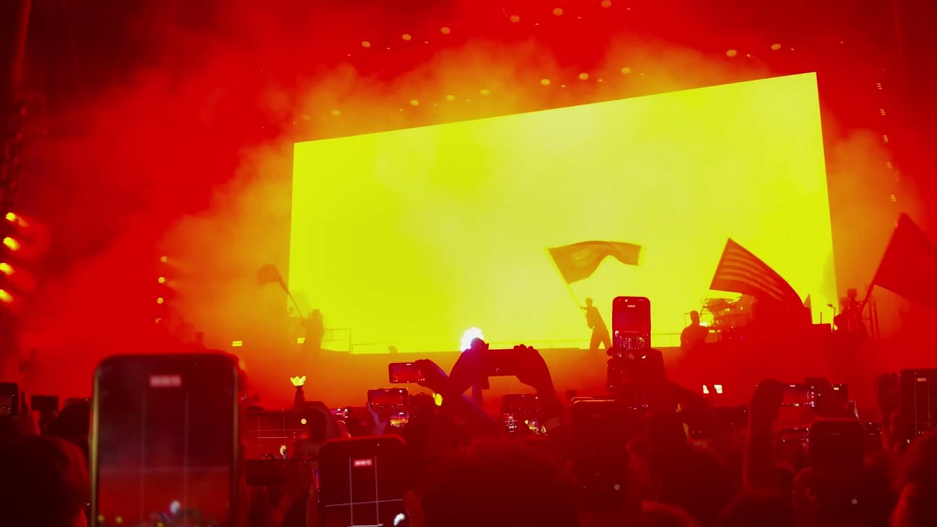 Concert stage lights illuminate a crowd, representing the immersive scale of modern K-pop live experiences