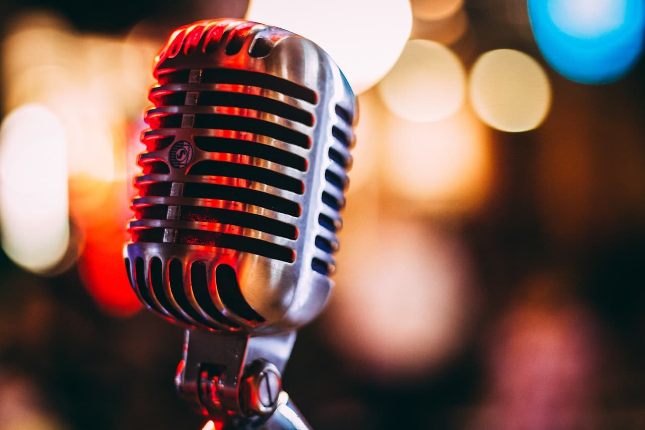 A vintage microphone illuminated by warm stage lighting, symbolizing the music and artistry of AKMU