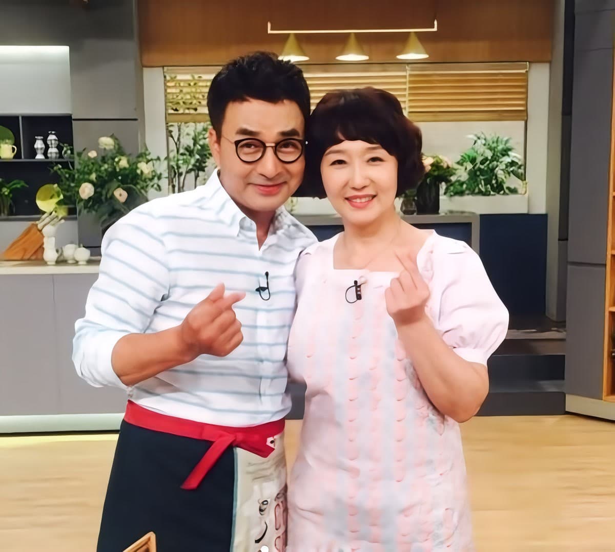 Bae Dong-sung and Jeon Jin-ju making finger hearts together on a TV cooking show set